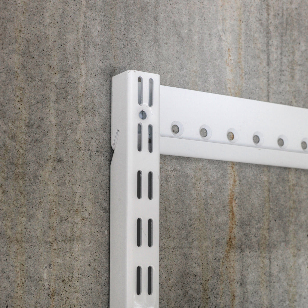 Close-up of steel shelving standard and wall-mounted hangtrack showing slot detail and mounting system