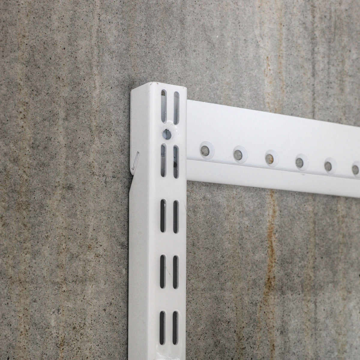 Close-up of steel shelving standard and wall-mounted hangtrack showing slot detail and mounting system