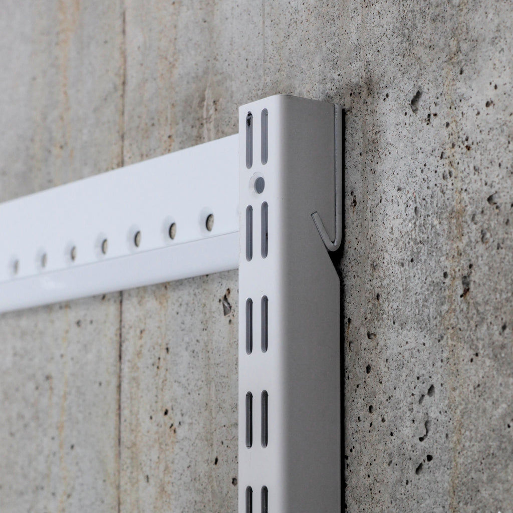 Close-up of steel shelving standard and wall-mounted hangtrack showing slot detail and mounting system