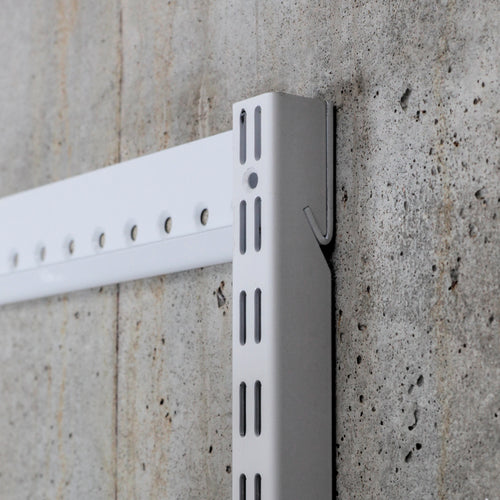 Close-up of steel shelving standard and wall-mounted hangtrack showing slot detail and mounting system