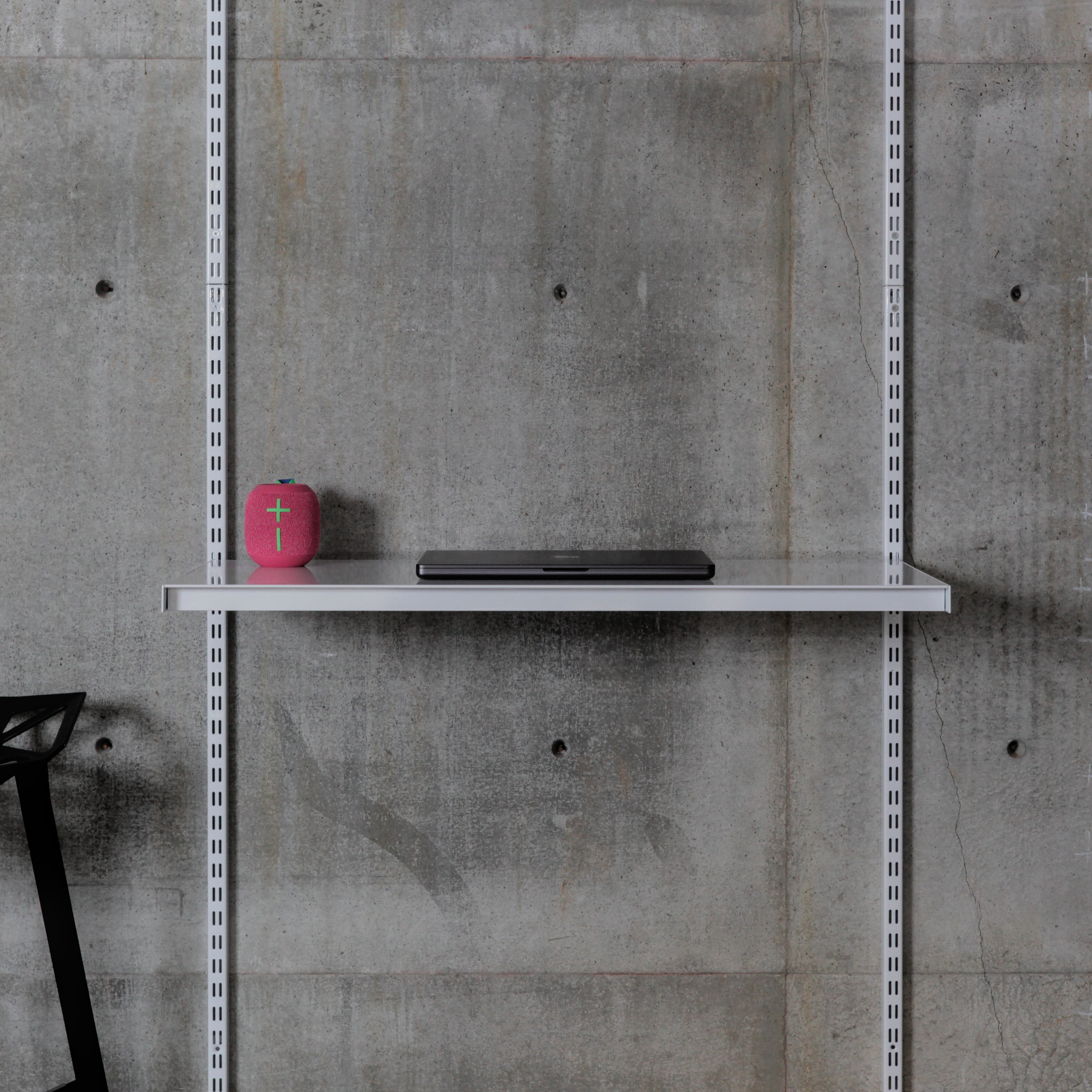 Wall-mounted steel shelf with speaker and laptop on modular shelving system